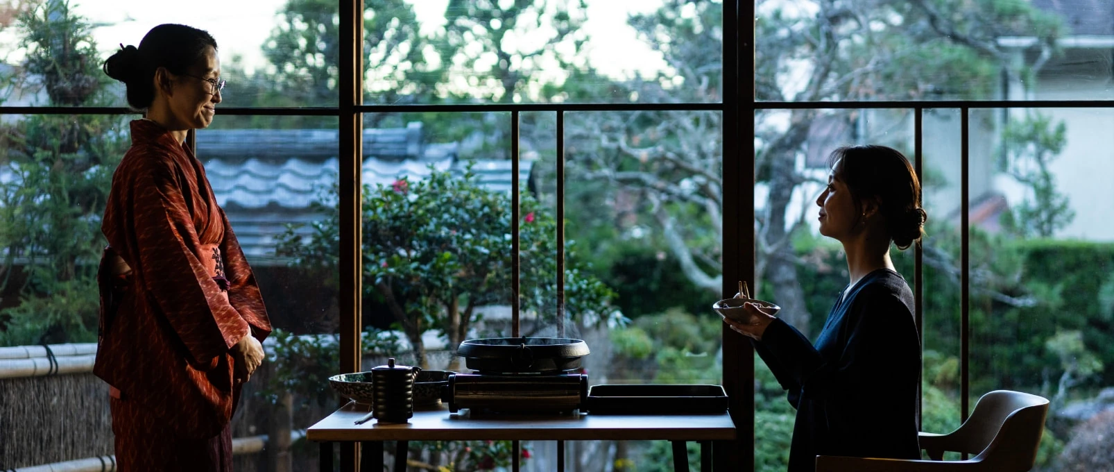 A guest enjoying a hot pot meal beside the garden-facing windows